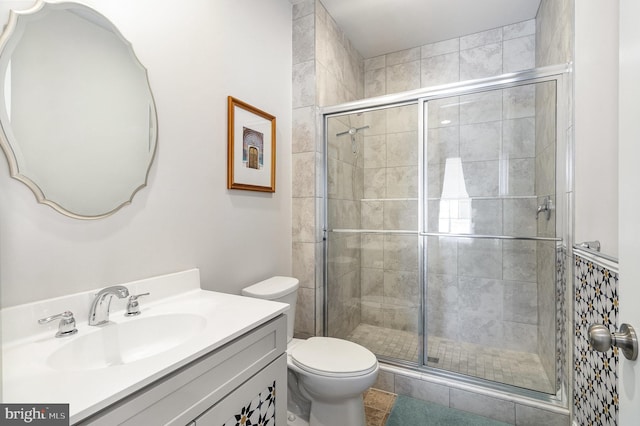 bathroom featuring toilet, a stall shower, vanity, and tile patterned flooring