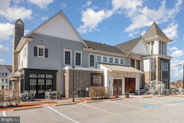 exterior space featuring uncovered parking, stone siding, french doors, and a chimney