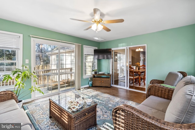 living area with baseboards, a ceiling fan, and wood finished floors