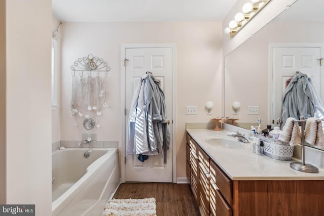 bathroom featuring a washtub, vanity, and wood finished floors