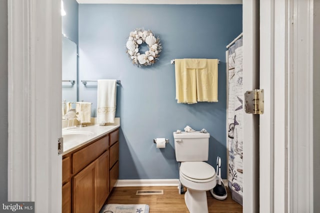 bathroom featuring visible vents, toilet, wood finished floors, baseboards, and vanity