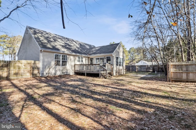 rear view of property with a fenced backyard, roof with shingles, and a deck