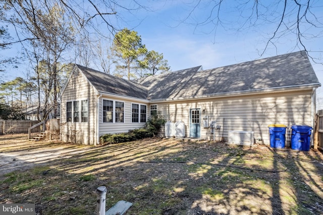 rear view of property with fence and a shingled roof