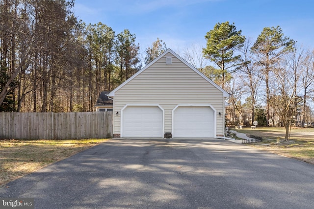 garage featuring aphalt driveway and fence