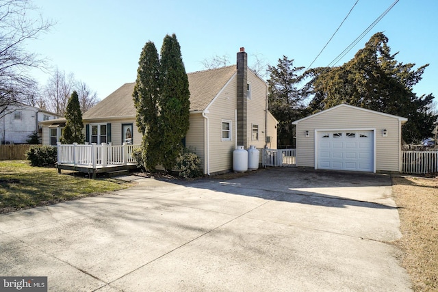 view of side of home with an outbuilding, fence, driveway, a shingled roof, and a detached garage