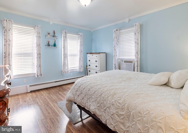 bedroom with ornamental molding, multiple windows, wood finished floors, and a baseboard radiator