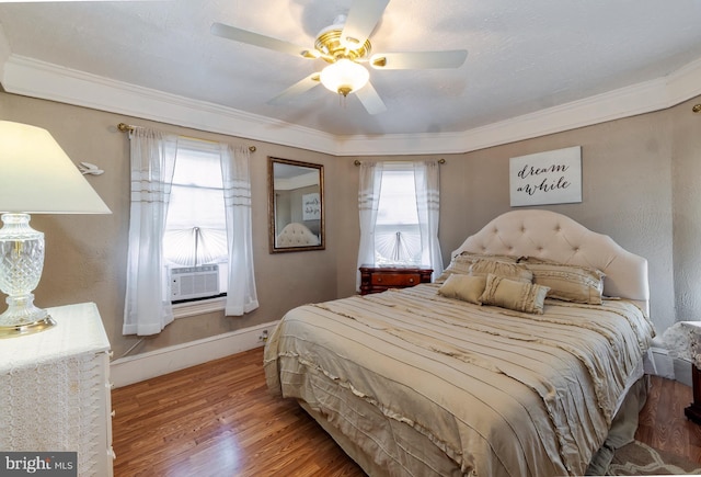 bedroom with ornamental molding, cooling unit, baseboards, and wood finished floors