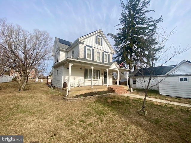 view of front of property with roof mounted solar panels, covered porch, and a front lawn