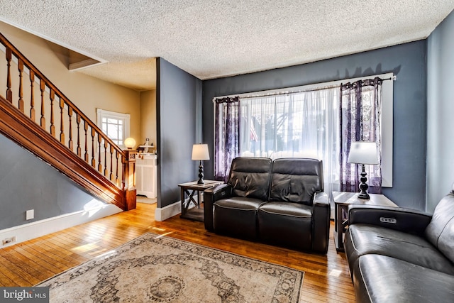 living room with hardwood / wood-style flooring, stairway, baseboards, and a textured ceiling