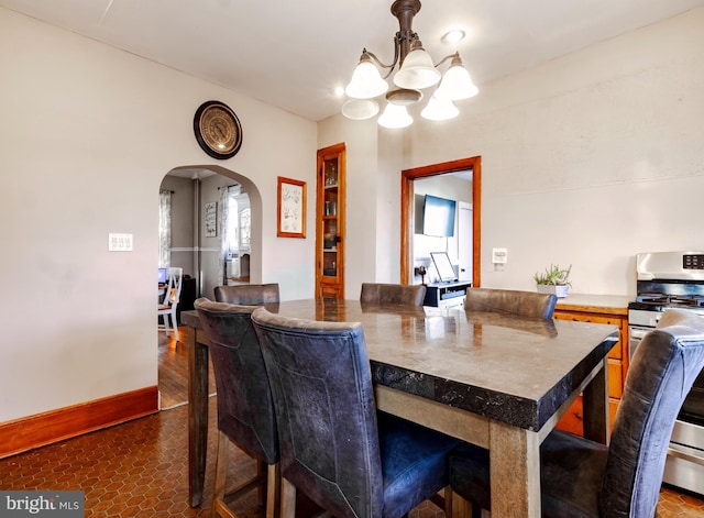 dining area with arched walkways, a notable chandelier, and baseboards