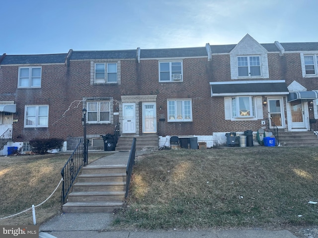 townhome / multi-family property with brick siding and a front lawn