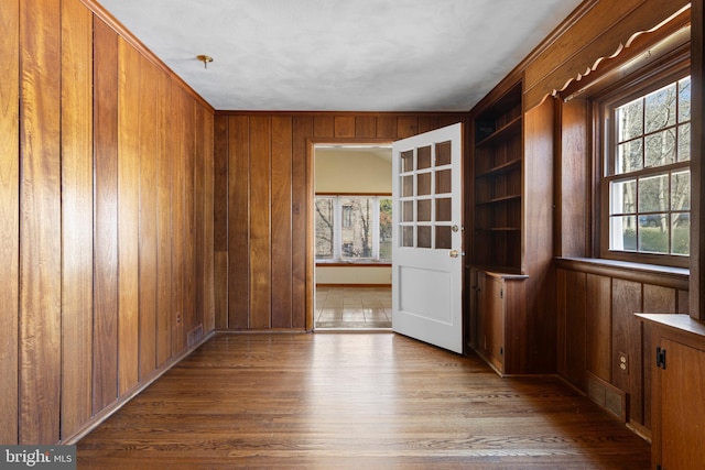 empty room with wooden walls, built in features, wood finished floors, and visible vents