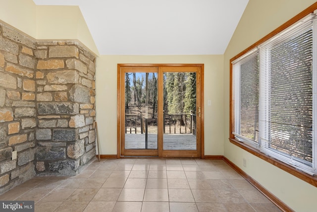 doorway to outside with tile patterned floors, baseboards, and lofted ceiling