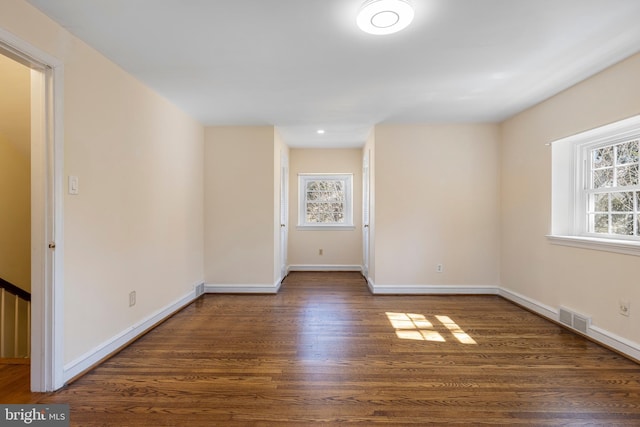 unfurnished room with a wealth of natural light, visible vents, baseboards, and wood finished floors