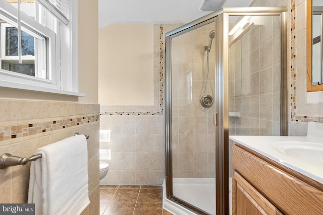 bathroom with tile patterned flooring, a stall shower, tile walls, and vanity