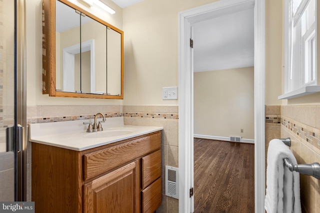 bathroom with vanity, tile walls, wood finished floors, and visible vents