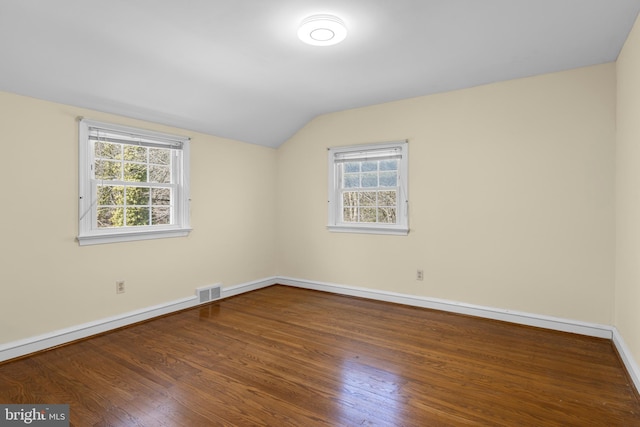 spare room featuring lofted ceiling, wood finished floors, visible vents, and baseboards