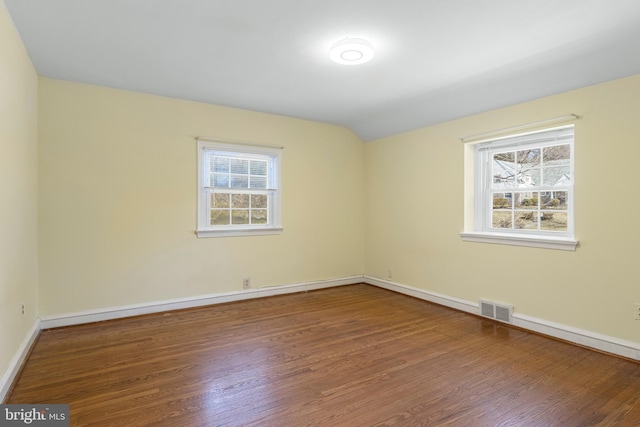 spare room featuring visible vents, a healthy amount of sunlight, and wood finished floors