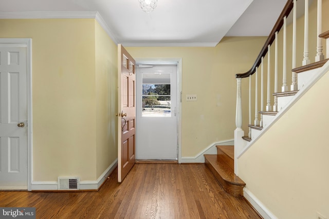 foyer entrance with crown molding, wood finished floors, visible vents, and baseboards