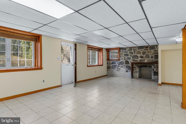 unfurnished living room with light tile patterned floors, a fireplace, baseboards, and a paneled ceiling