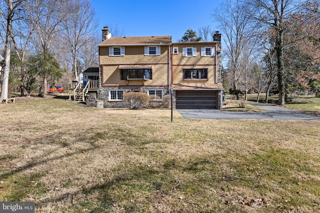 rear view of house featuring aphalt driveway, a lawn, a chimney, a garage, and stone siding