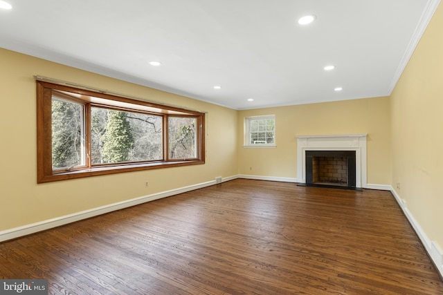 unfurnished living room featuring a fireplace with flush hearth, dark wood-type flooring, ornamental molding, recessed lighting, and baseboards