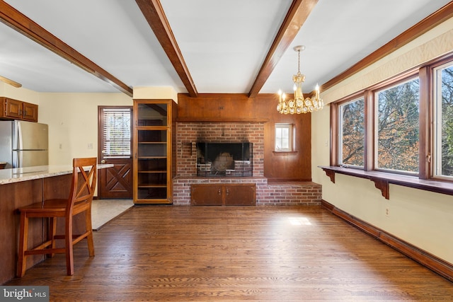 living room with dark wood-type flooring, beamed ceiling, a fireplace, and baseboards