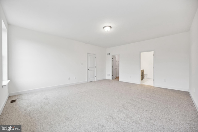 unfurnished bedroom with visible vents, light carpet, baseboards, and a walk in closet