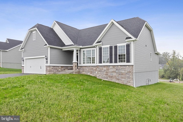 view of front of home with a front lawn, stone siding, driveway, and a shingled roof