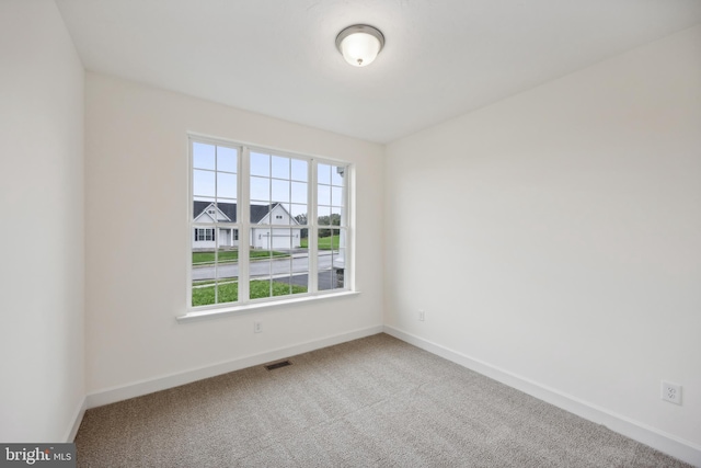 carpeted empty room featuring visible vents and baseboards