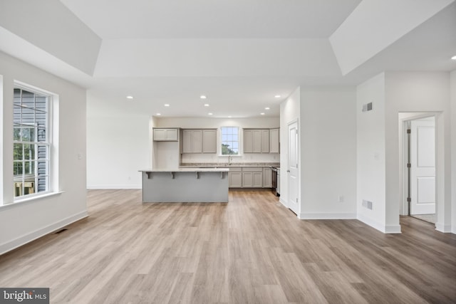 unfurnished living room featuring light wood finished floors, visible vents, recessed lighting, and baseboards