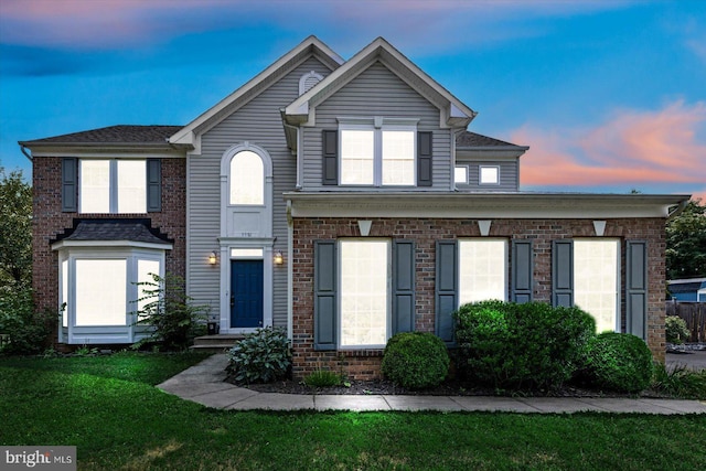 view of front of house featuring brick siding and a lawn