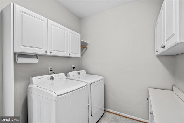 washroom featuring baseboards, cabinet space, and separate washer and dryer