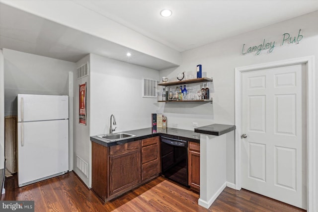 kitchen with visible vents, a sink, black dishwasher, dark countertops, and freestanding refrigerator