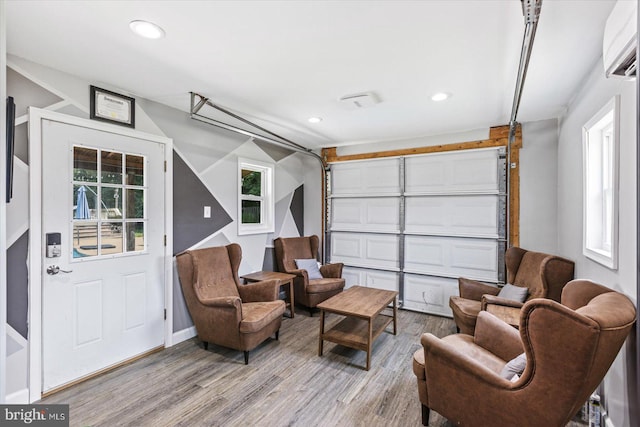 interior space featuring a wall mounted air conditioner, a garage, light wood-style flooring, and recessed lighting