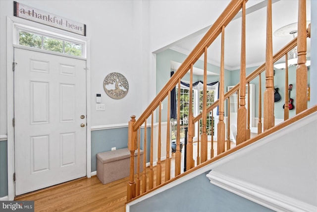 entryway featuring crown molding, stairway, and wood finished floors