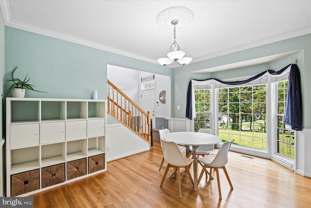 dining room featuring visible vents, a notable chandelier, wood finished floors, and crown molding