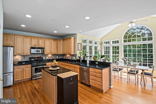 kitchen featuring decorative backsplash, appliances with stainless steel finishes, a peninsula, and a center island