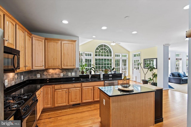 kitchen featuring range with gas cooktop, black microwave, vaulted ceiling, decorative backsplash, and a sink