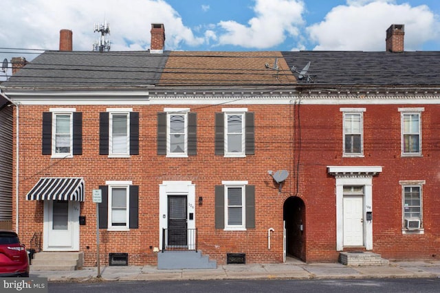 view of front of home featuring brick siding, entry steps, and a chimney