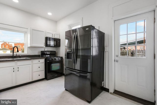 kitchen featuring recessed lighting, white cabinets, marble finish floor, black appliances, and a sink