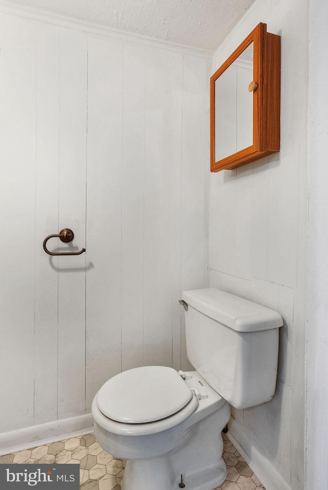 bathroom with a decorative wall, a textured ceiling, and toilet