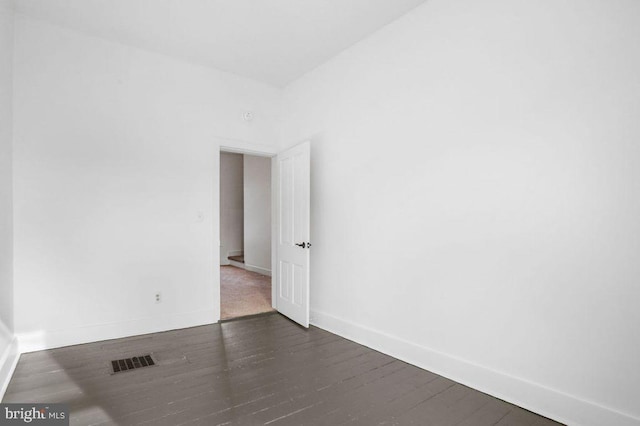 spare room with visible vents, baseboards, and dark wood-style flooring