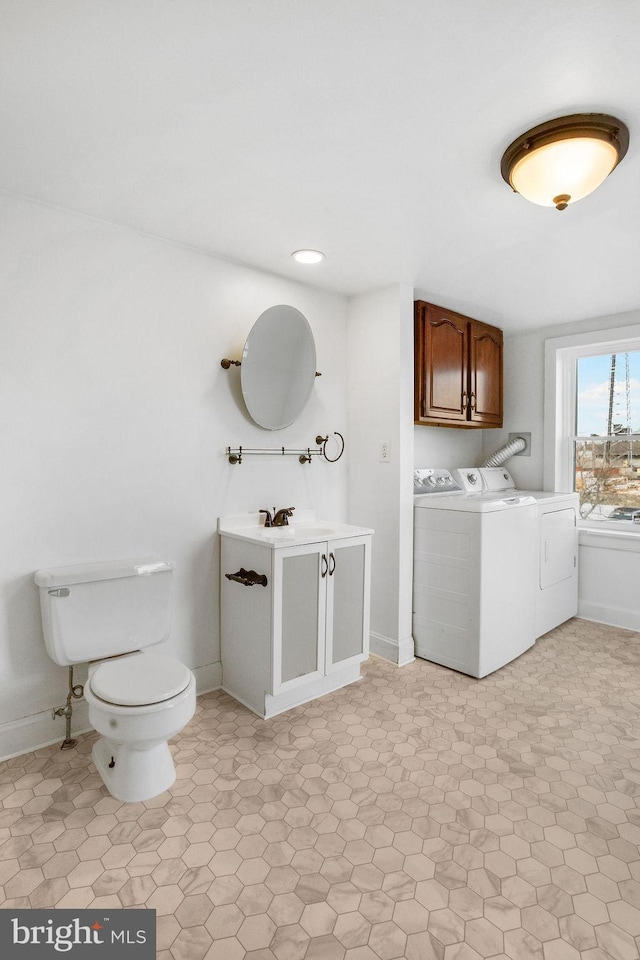 bathroom featuring baseboards, toilet, vanity, and washing machine and clothes dryer