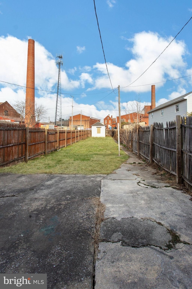 view of yard with an outdoor structure, a storage shed, and a fenced backyard