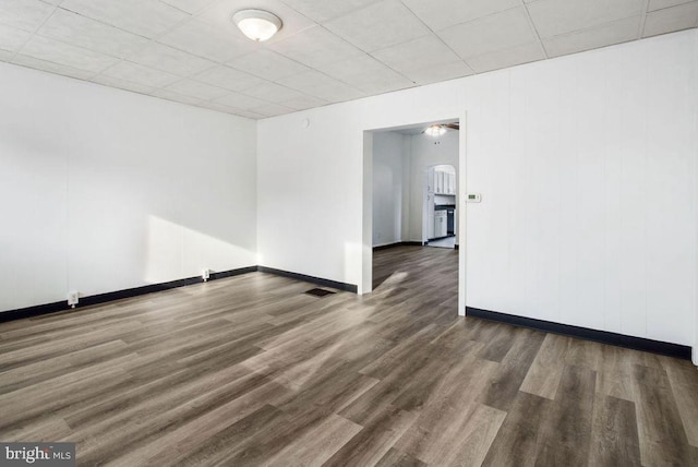 spare room with visible vents, a drop ceiling, baseboards, and wood finished floors