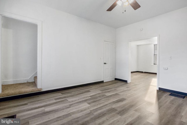 empty room featuring visible vents, baseboards, stairs, wood finished floors, and a ceiling fan