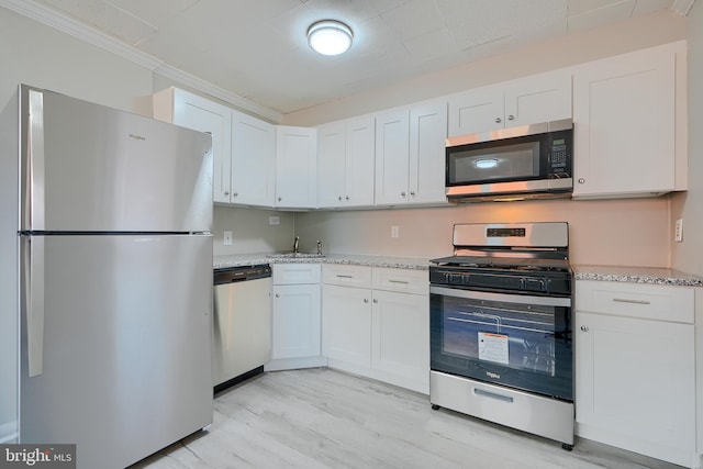 kitchen featuring white cabinets, light wood finished floors, light stone countertops, and appliances with stainless steel finishes