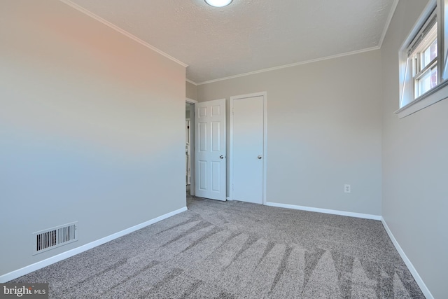 empty room featuring visible vents, carpet flooring, crown molding, and baseboards