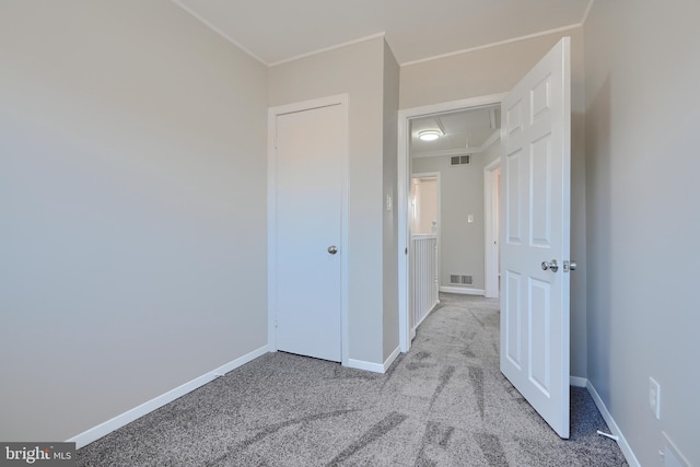 unfurnished bedroom with visible vents, baseboards, light colored carpet, and ornamental molding